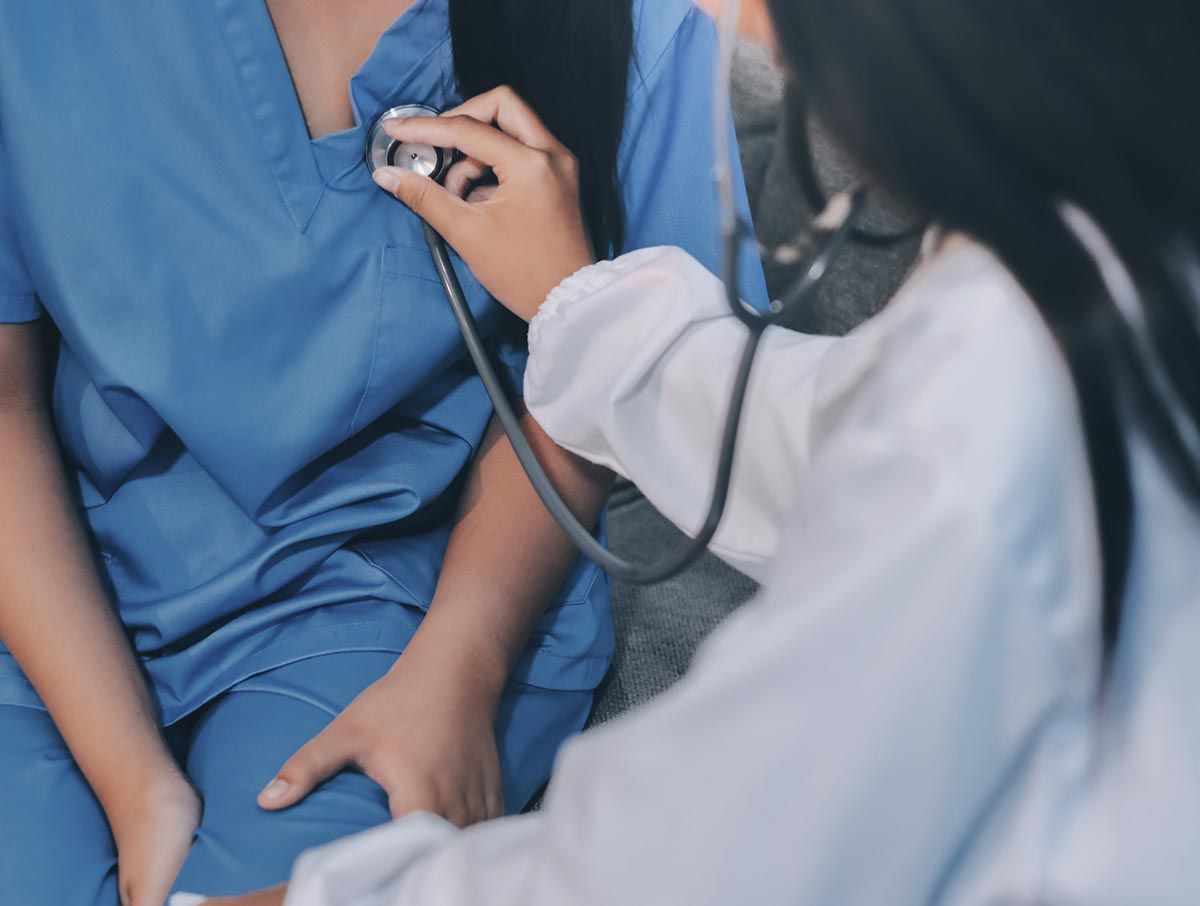 Un médico está escuchando el corazón de un paciente con un estetoscopio.