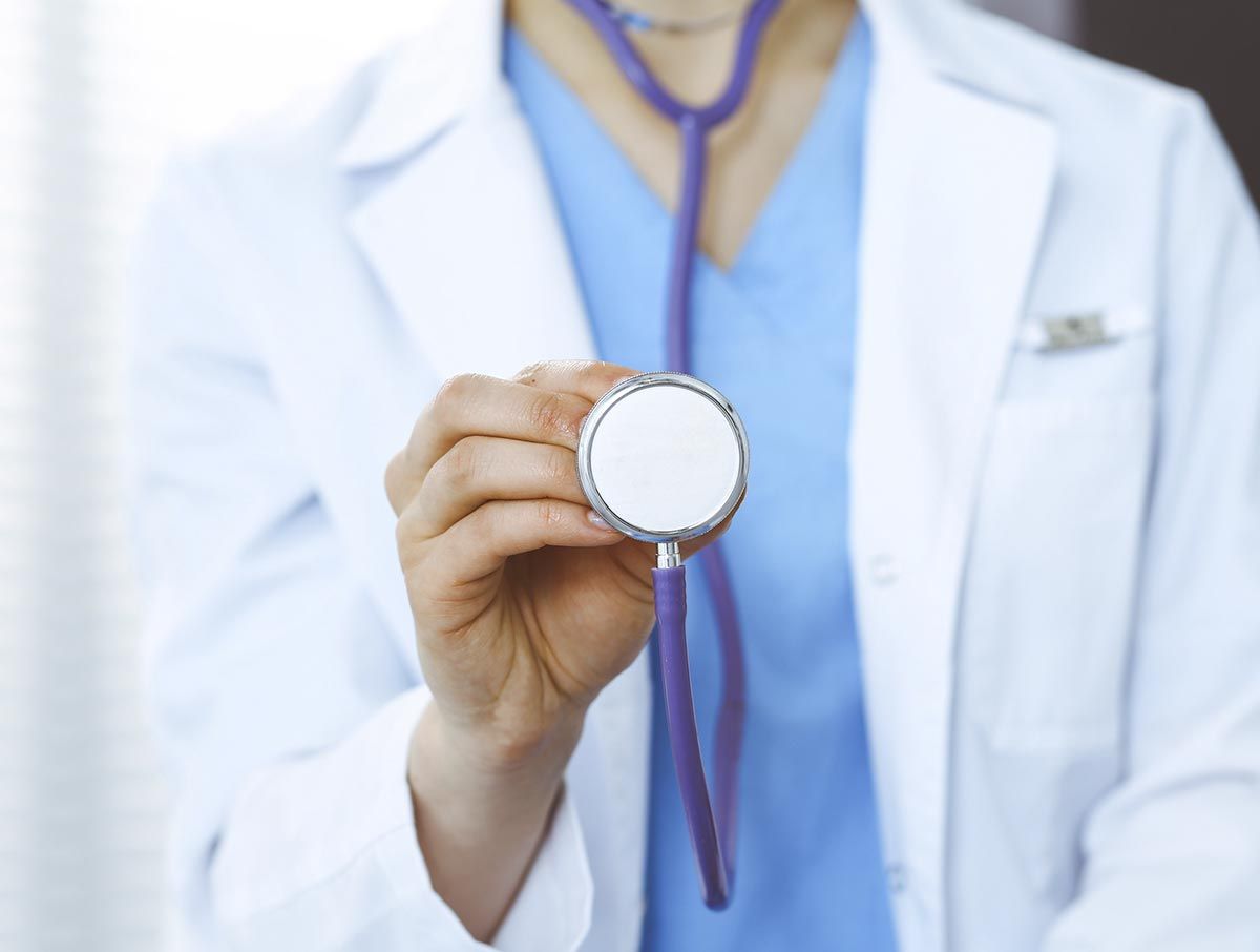 Un médico sostiene un estetoscopio en su mano.