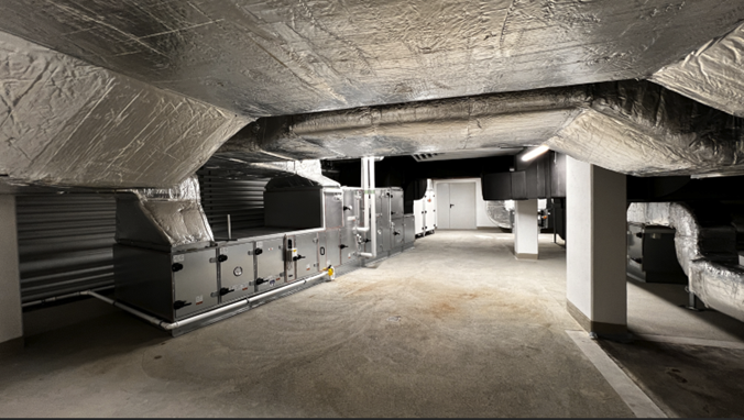 Eine Fotografie einer installierten Lüftungsanlage und isolierter Kanäle in einem Beton-Technikraum.