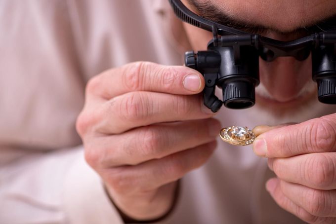 Joyero inspeccionando un anillo de oro con una lupa en primer plano.