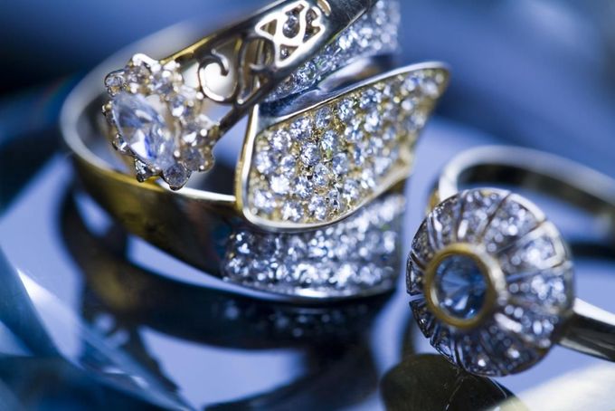 Anillos de plata surtidos con diamantes y piedras preciosas sobre un fondo de satén azul.