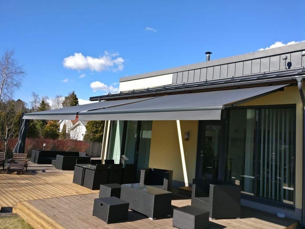 Moderni talon patio, jossa on sisäänvedettävä markiisi, mustat ulkokalusteet ja suuret liukuovet
