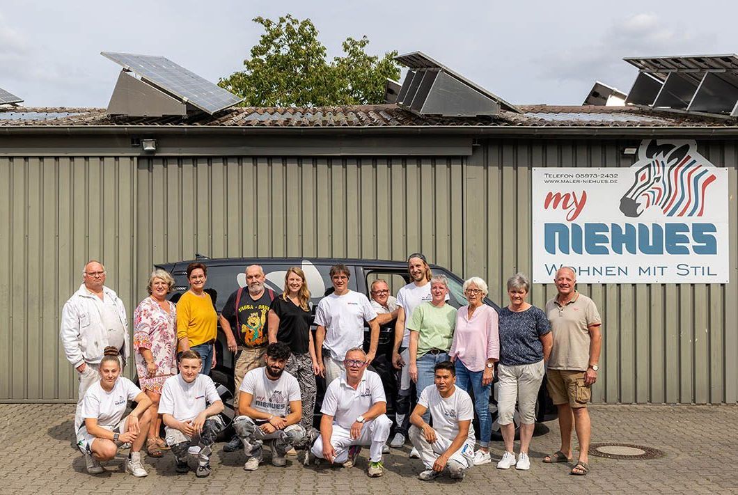 Gruppe von Menschen posiert vor einem Gebäude mit einem Zebraschild; bedeckter Himmel.