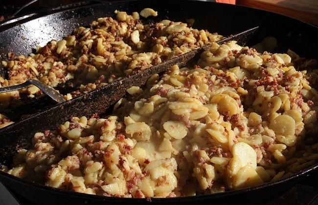 Eine Nahaufnahme einer mit Essen gefüllten Pfanne und einem Spatel.
