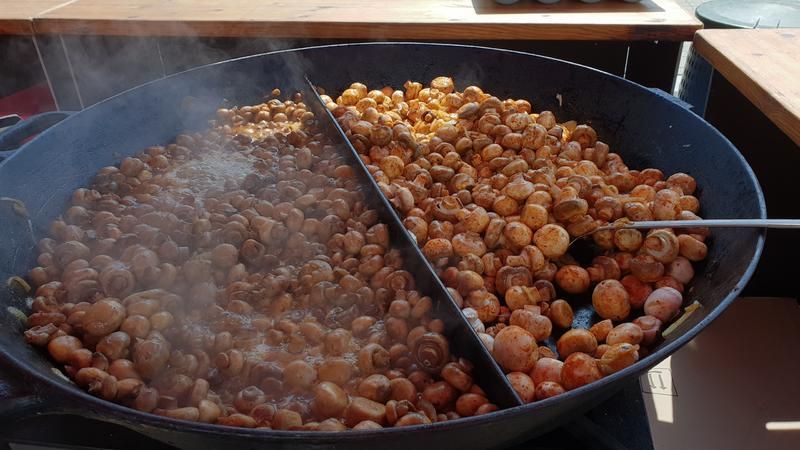 Ein großer Topf mit Pilzen wird mit einem Löffel umgerührt