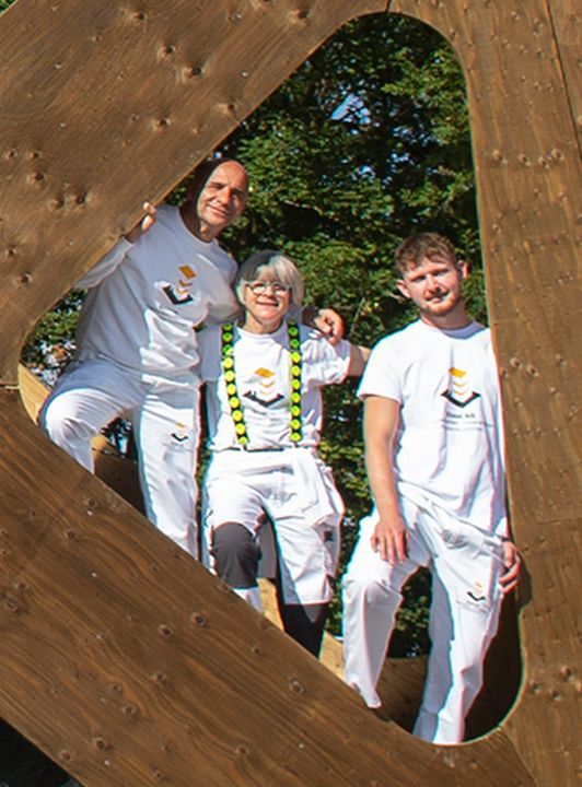 Eine Gruppe von Menschen steht in einem herzförmigen Loch in einer Holzkonstruktion