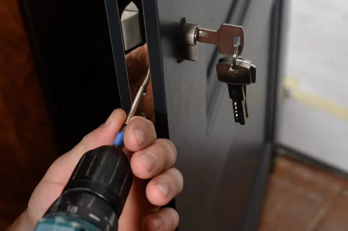 Una persona utiliza un taladro eléctrico de mano para trabajar en un tornillo ubicado en el panel lateral 