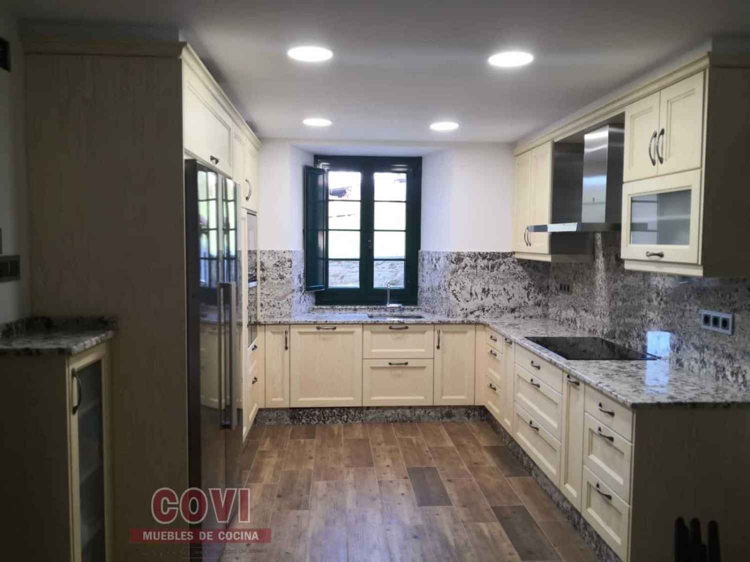 Gabinetes de cocina color beige y encimeras de granito con ventana.