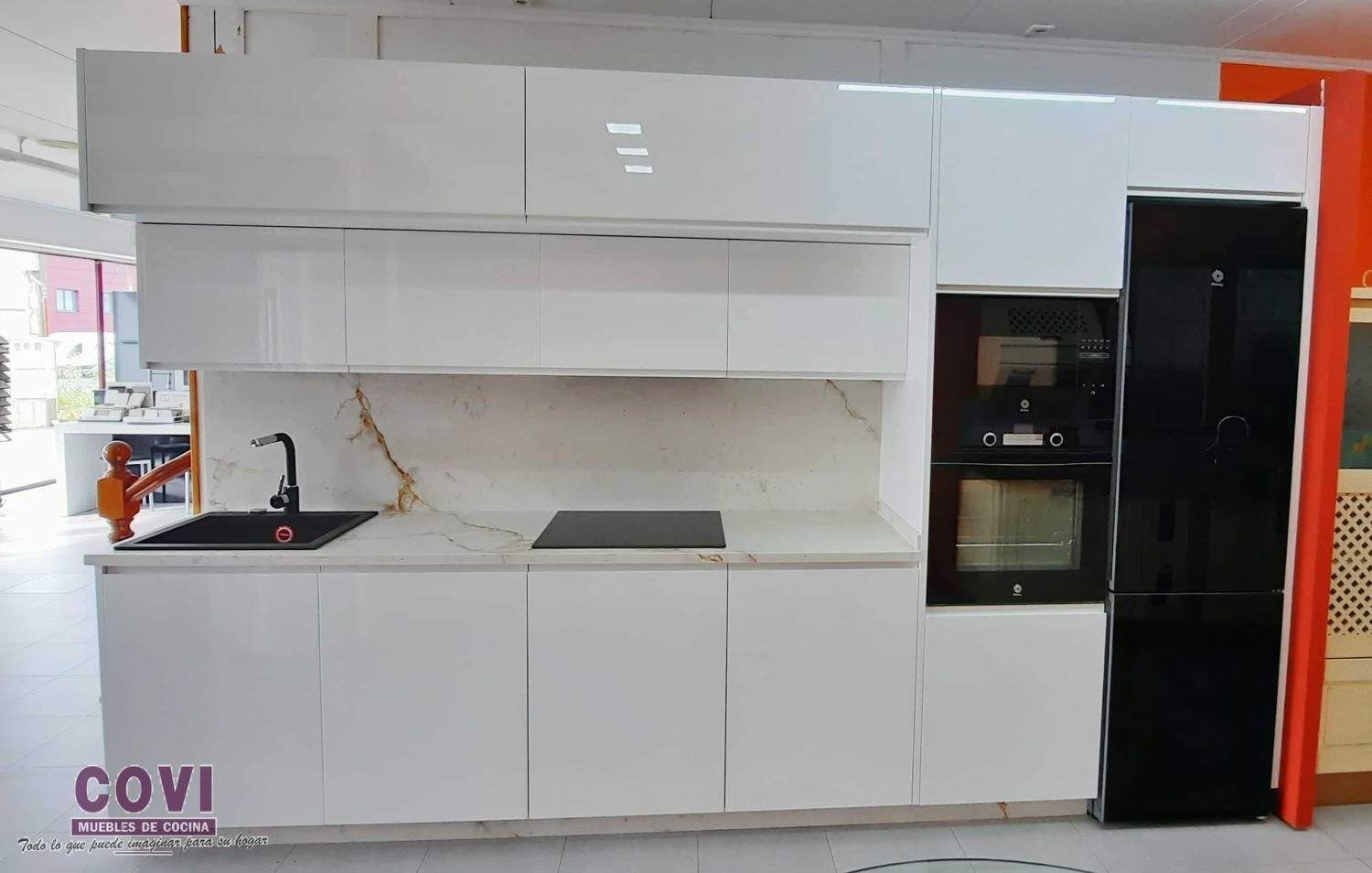 Gabinetes de cocina blancos modernos con horno empotrado, electrodomésticos negros y encimera de mármol.