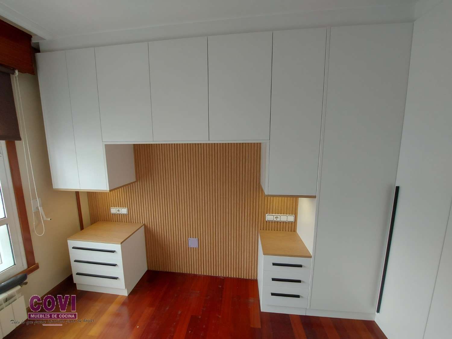 Dormitorio empotrado con armarios altos, mesitas de noche y una pared de madera acentuada.