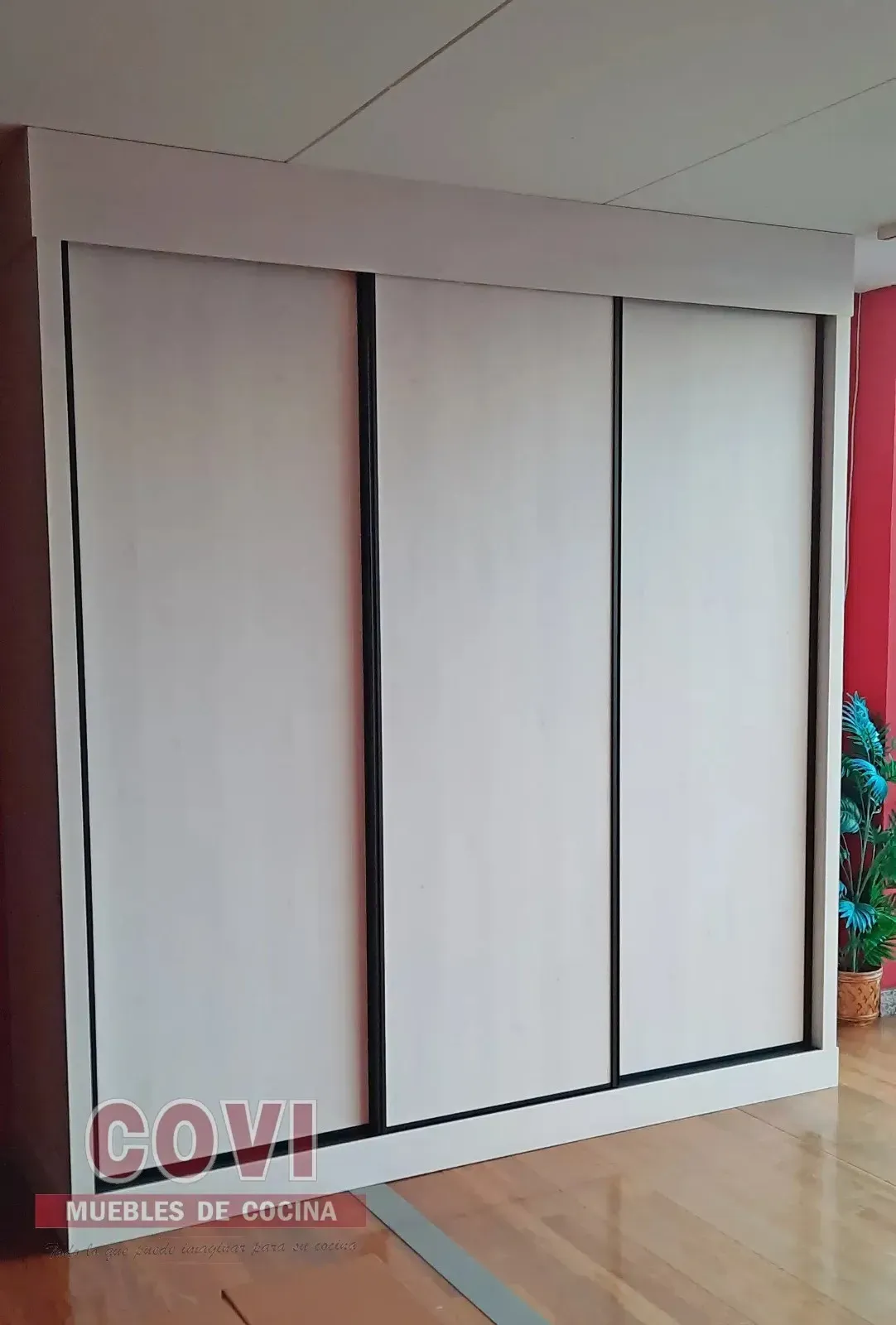 Armario con puertas corredizas de color blanco en una habitación con suelo de madera.