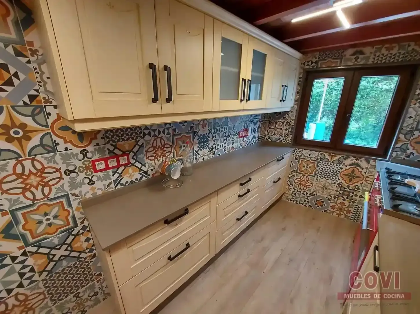 Gabinetes de cocina de color beige con protector contra salpicaduras con estampado colorido.