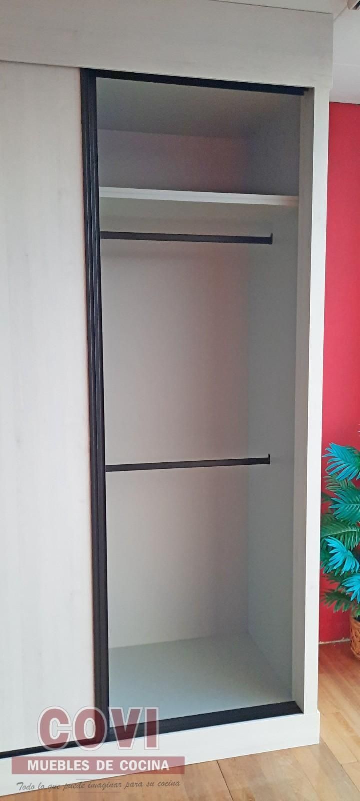 Armario blanco con dos estantes y una barra en el interior. Puerta corredera a la izquierda.