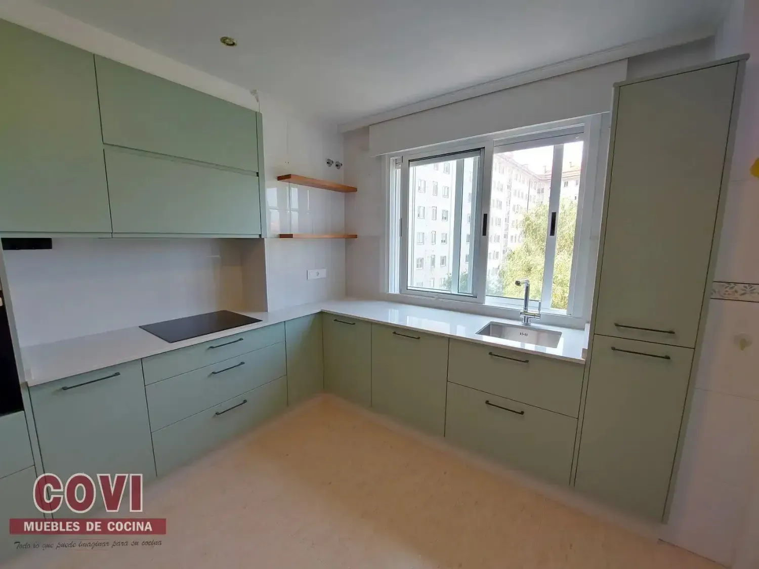 Cocina verde con encimeras blancas y una ventana sobre un fregadero.