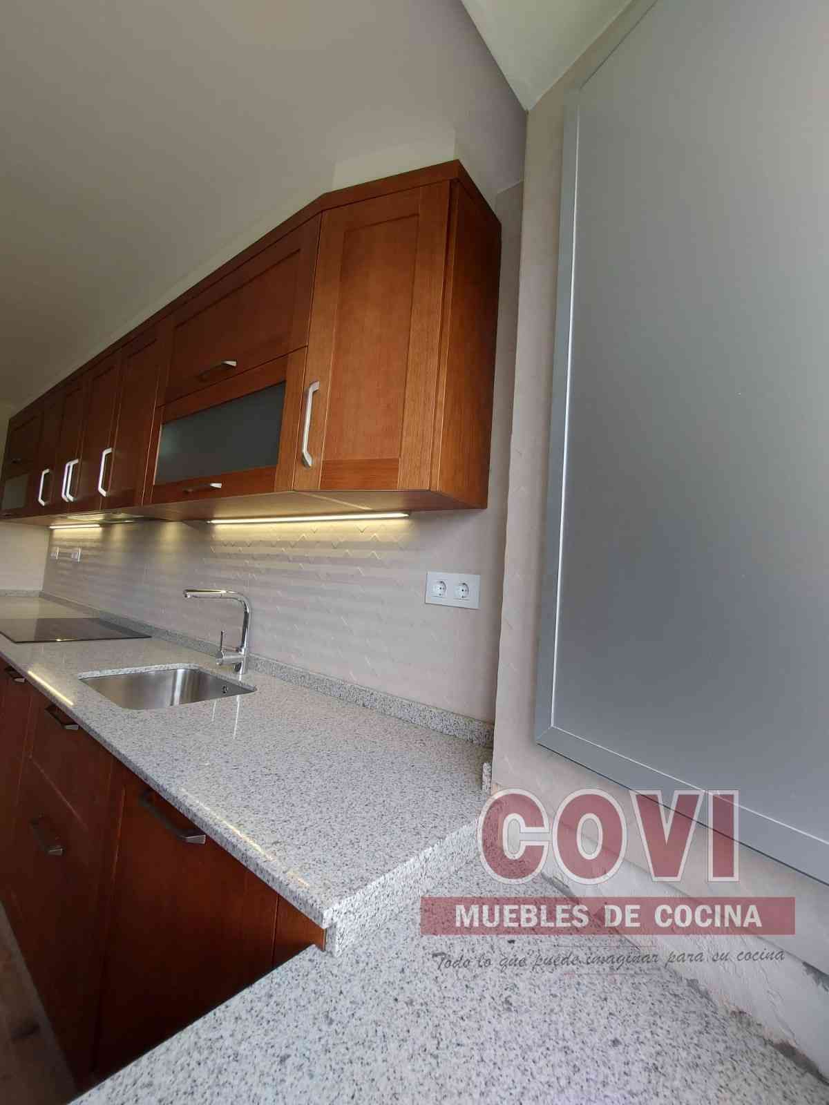 Cocina moderna con encimeras claras, gabinetes oscuros y fregadero de acero inoxidable.