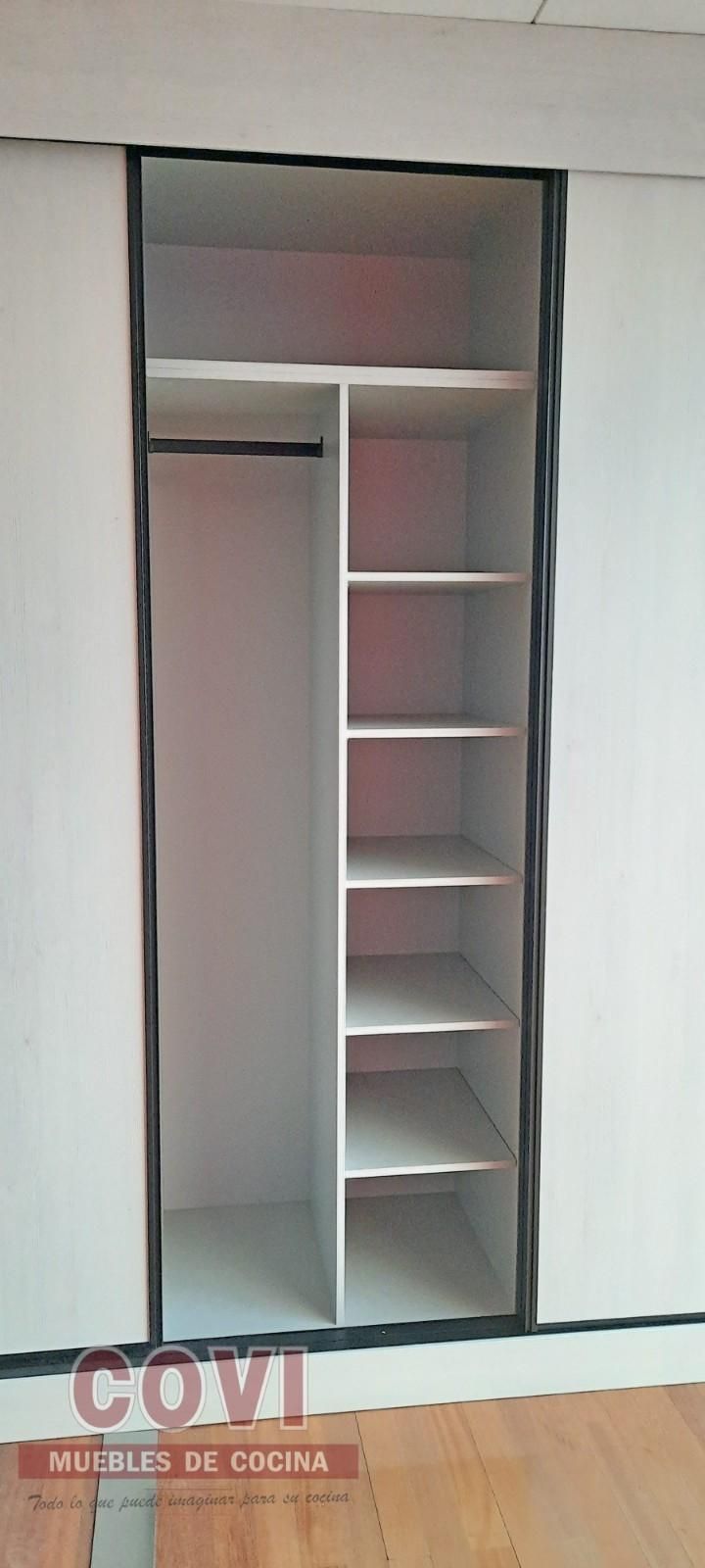 Armario blanco abierto con estantes y barra para colgar. Marco negro.