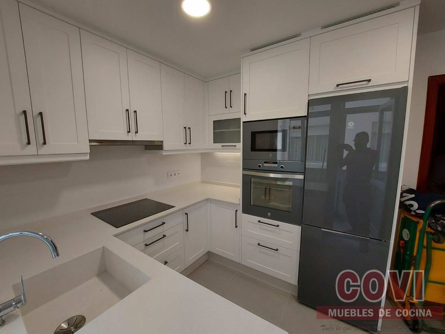 Cocina blanca con electrodomésticos de acero inoxidable y herrajes oscuros.