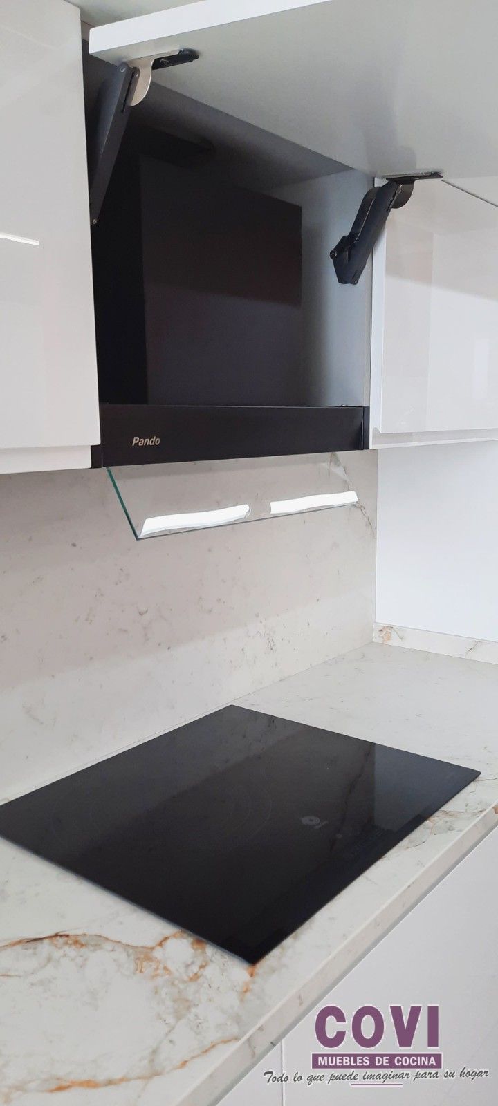 Cocina con estufa negra, campana extractora y gabinetes blancos. La encimera es de color claro.