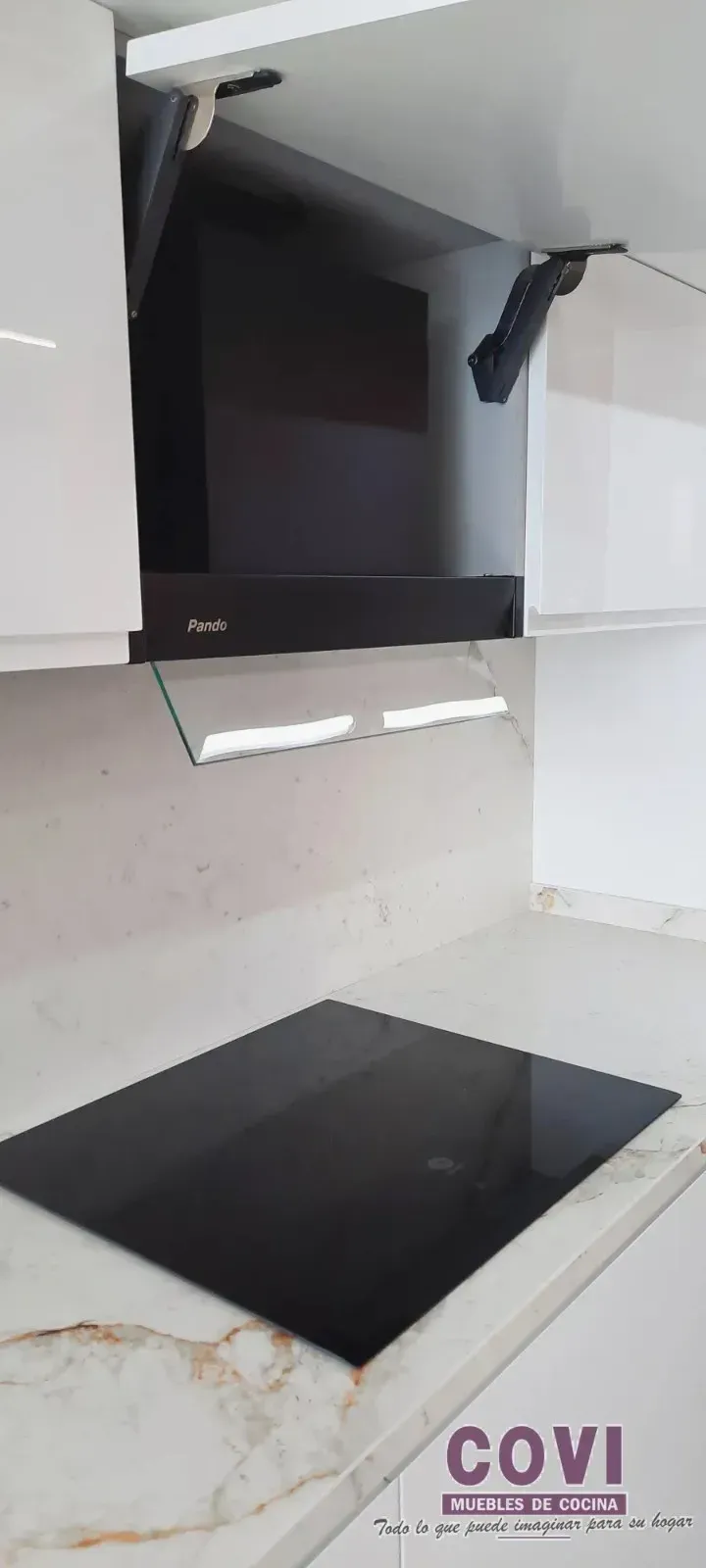 Cocina con anafe negro, campana extractora integrada y gabinetes blancos.