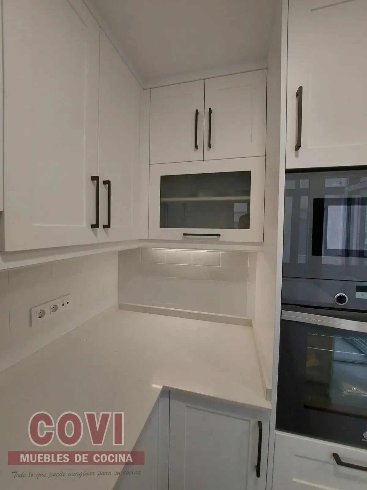 Gabinetes de cocina blancos con herrajes negros y horno empotrado.