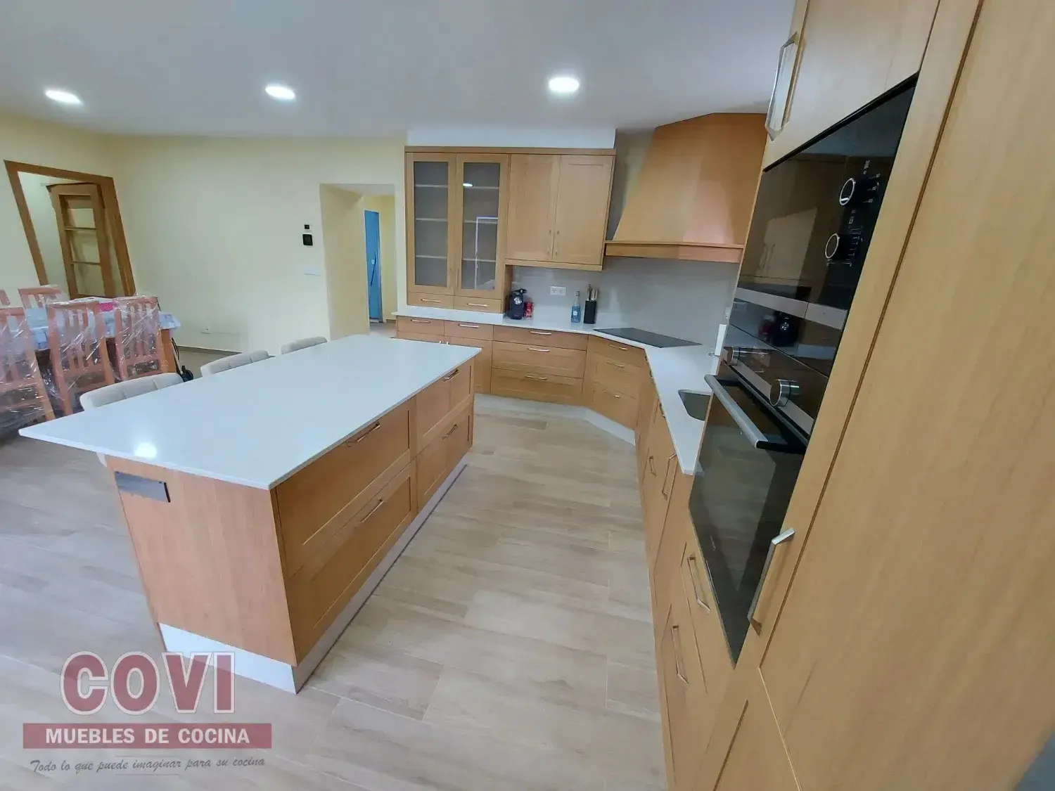 Cocina moderna con gabinetes de madera clara, encimeras de cuarzo y una isla grande.