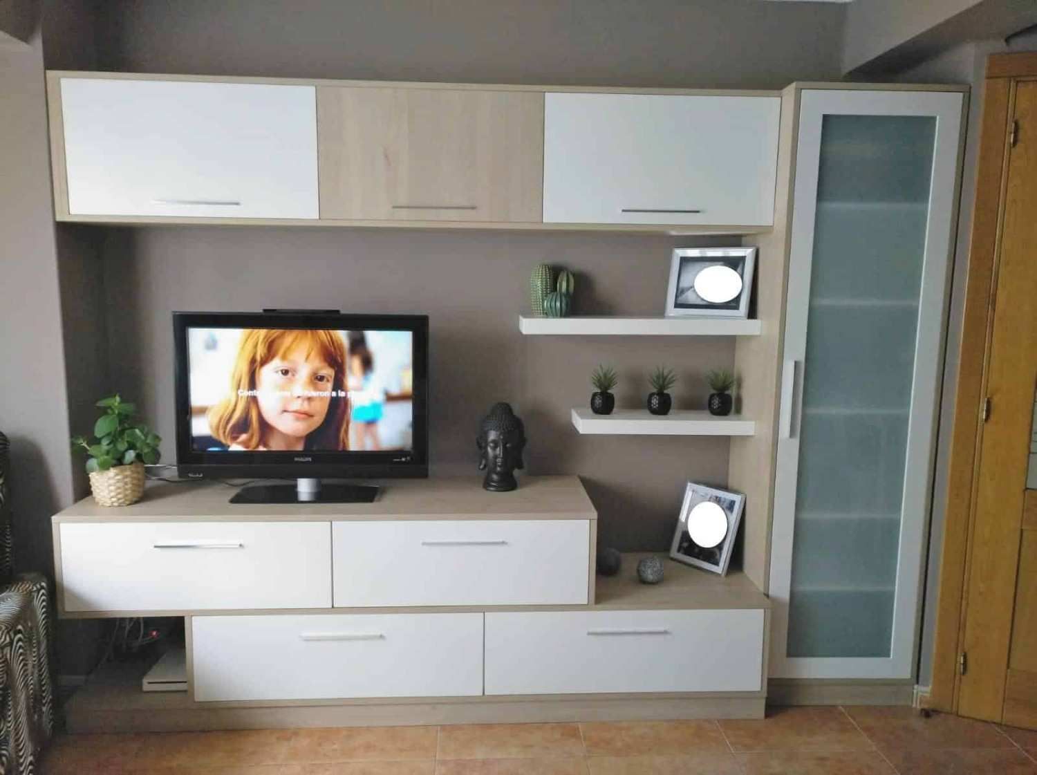 Sala de estar con moderna consola de TV en blanco y beige y gabinetes de almacenamiento.