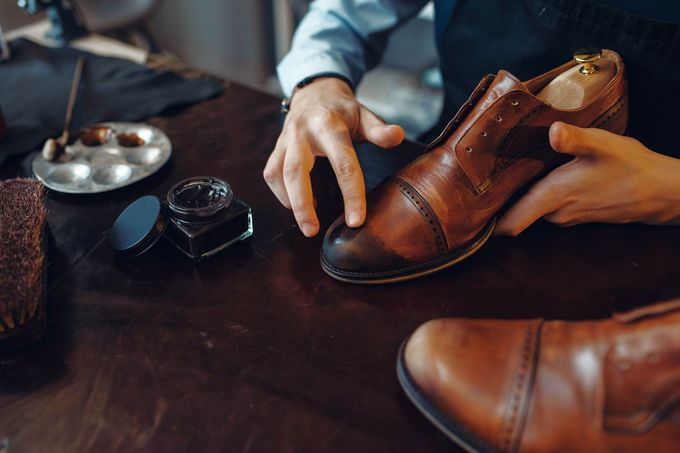 Un hombre está lustrando un par de zapatos de cuero marrón.