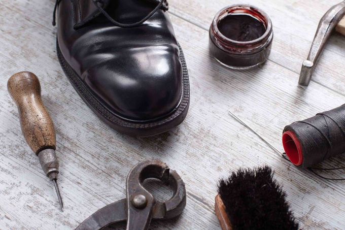 Un par de zapatos negros sobre una mesa de madera junto a un par de herramientas para lustrar zapatos.