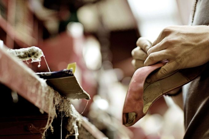 Una persona está trabajando en un par de zapatos en una fábrica.