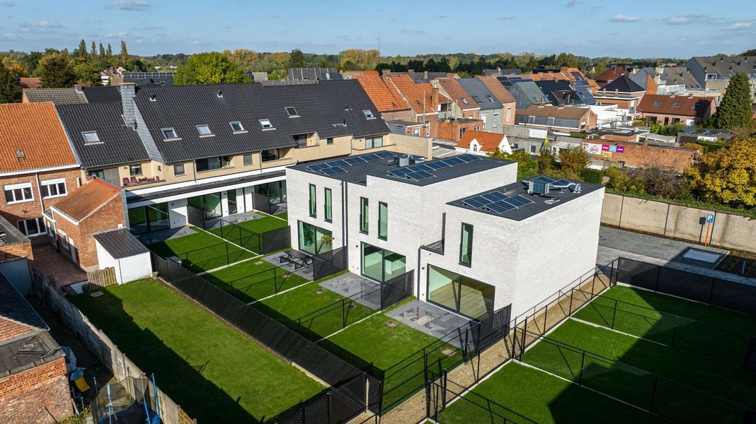 Luchtfoto van moderne witte rijtjeshuizen met groene gazons in een buitenwijk.