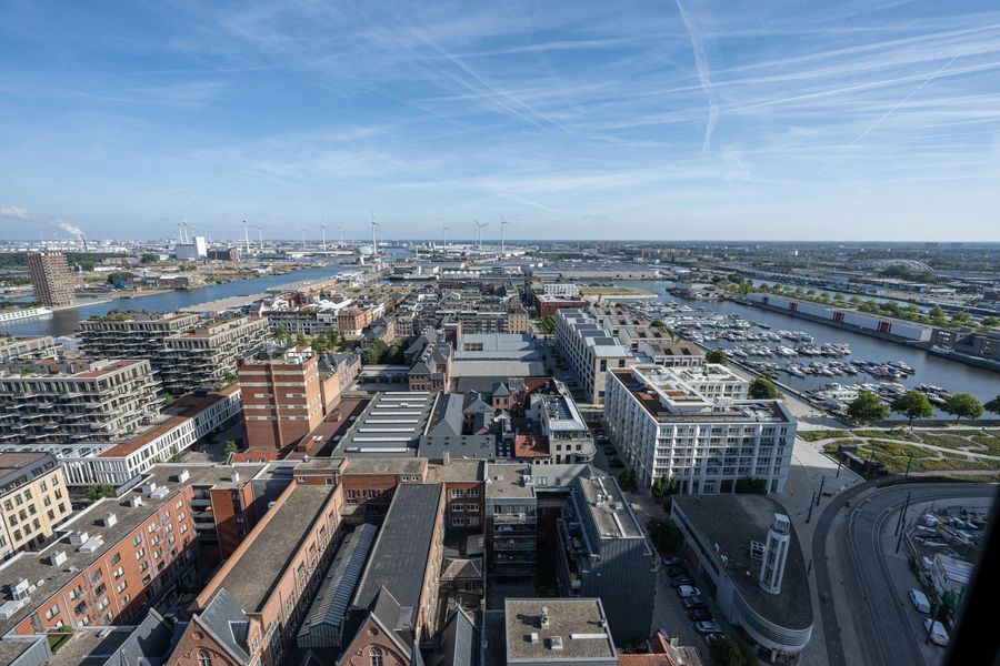 Luchtfoto van een stadskanaalgebied met gebouwen, boten en een heldere blauwe lucht.