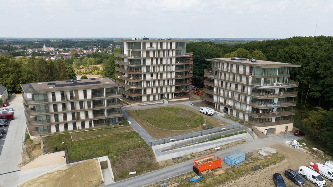 Luchtfoto van moderne appartementencomplexen rondom een ​​centrale binnenplaats en parkeerplaats.