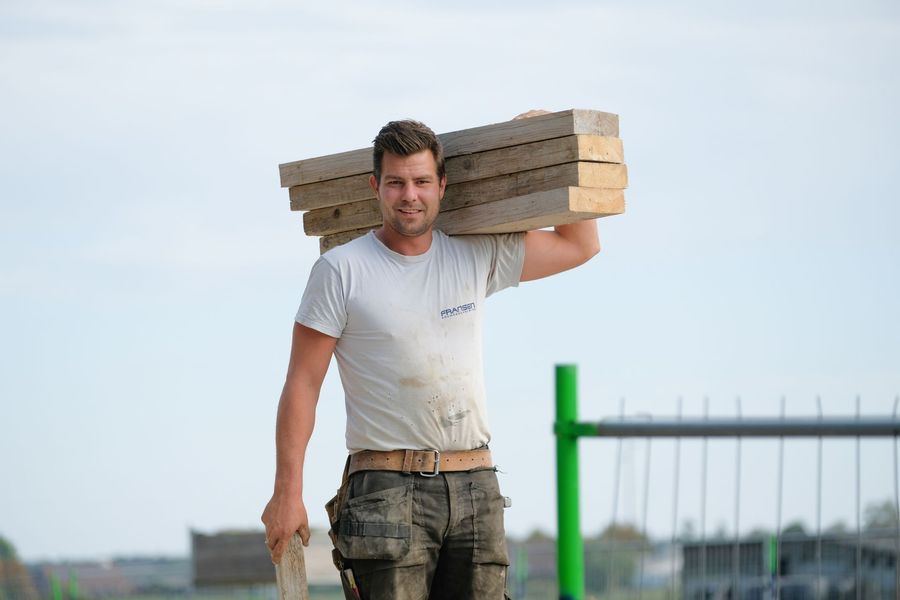Een arbeider gebruikt een slijpmachine, waardoor er vonken over de werkplaatsvloer vliegen.
