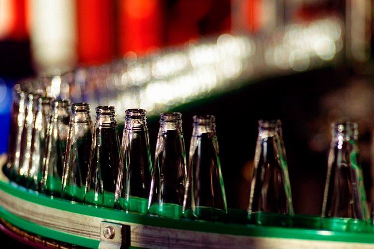Una cinta transportadora llena de botellas de vidrio vacías.