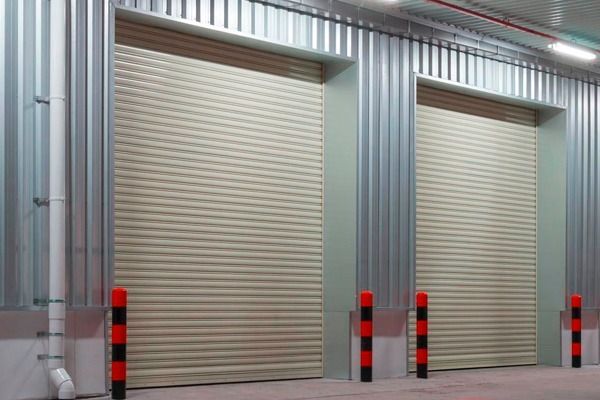 Una fila de puertas enrollables en un almacén con postes rojos y negros.