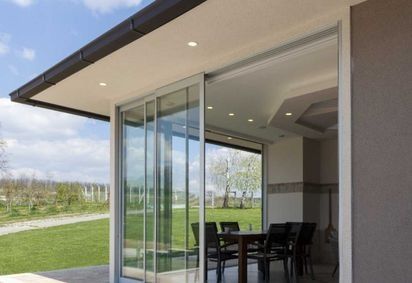 Una puerta corrediza de vidrio se abre a un patio con una mesa y sillas.
