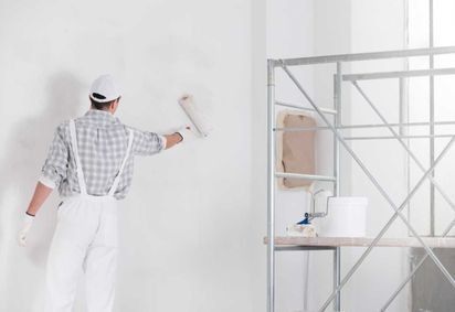 Un hombre está pintando una pared con un rodillo de pintura.