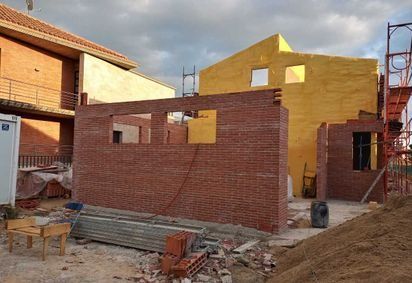 Se está construyendo un muro de ladrillos delante de un edificio amarillo.