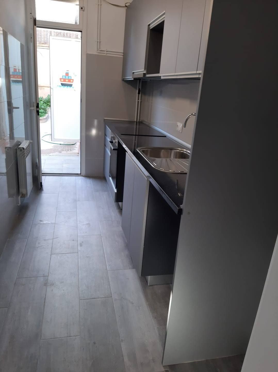 Una cocina con fregadero, estufa, gabinetes y una puerta.