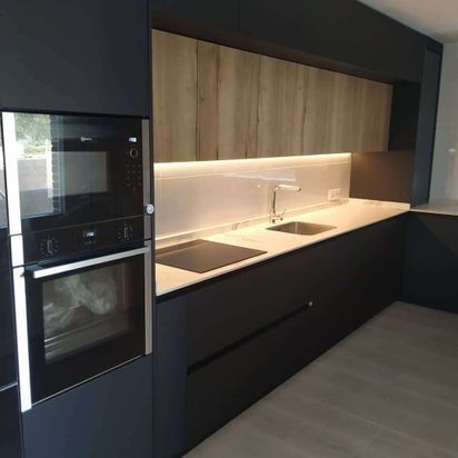 Una cocina con gabinetes negros y encimeras blancas.