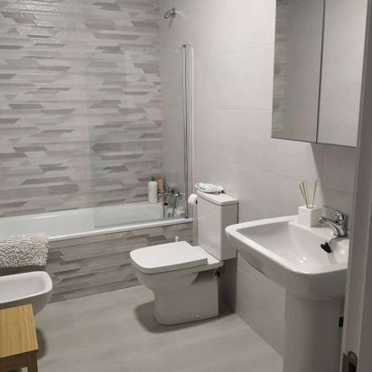 Un baño con inodoro, lavabo, bañera y espejo.