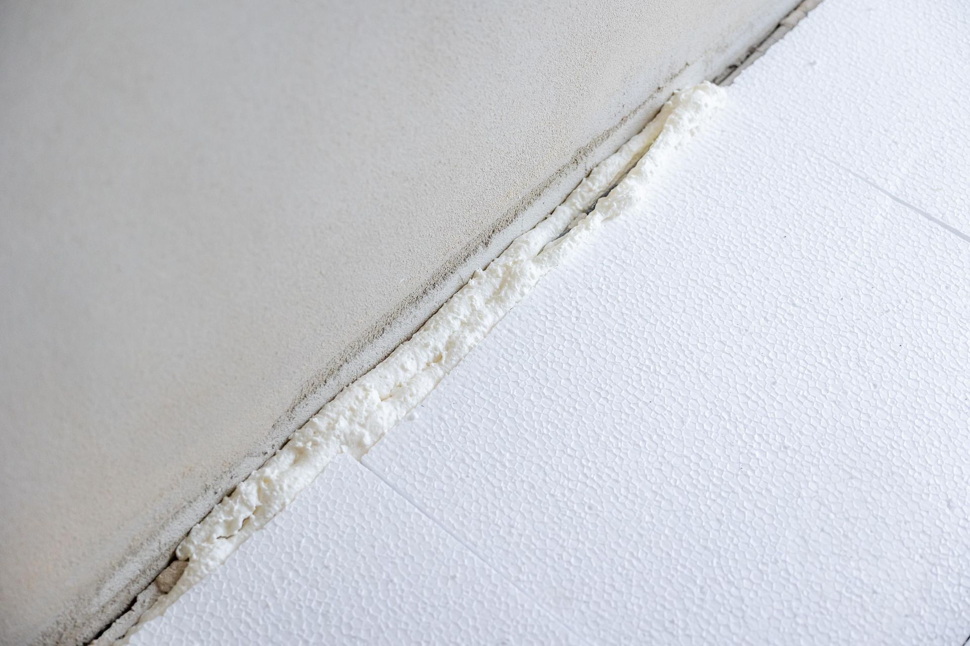 Weiße Schaumstoff-Dämmplatten mit einem mit Schaumstoff gefüllten Zwischenraum, schräg auf einer weißen Fläche.