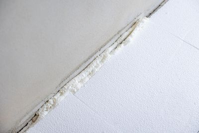 Weiße Schaumstoff-Dämmplatten mit einem mit Schaumstoff gefüllten Zwischenraum, schräg auf einer weißen Fläche.