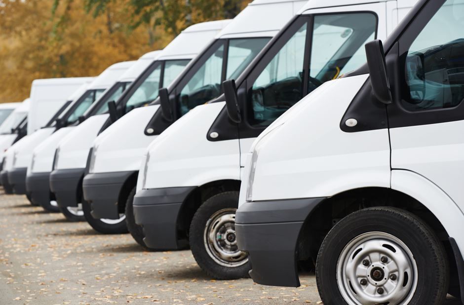 Fila de furgonetas de carga blancas estacionadas al aire libre.