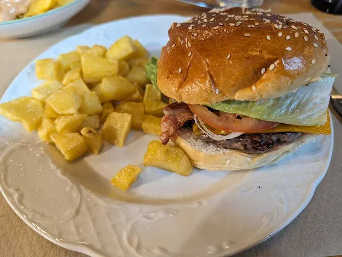 Un plato blanco cubierto con una hamburguesa y papas fritas.