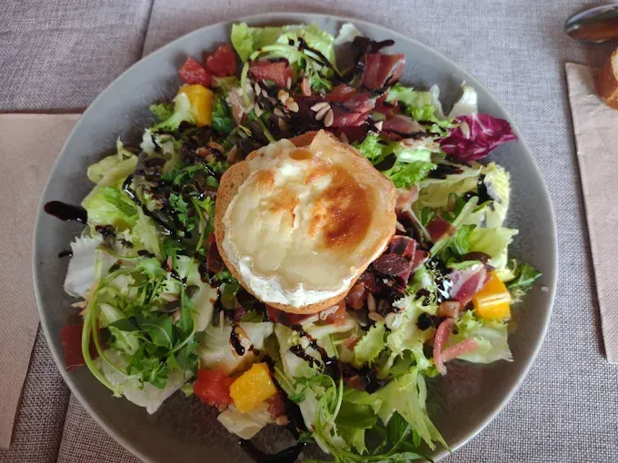 Una ensalada con un trozo de queso de cabra encima.