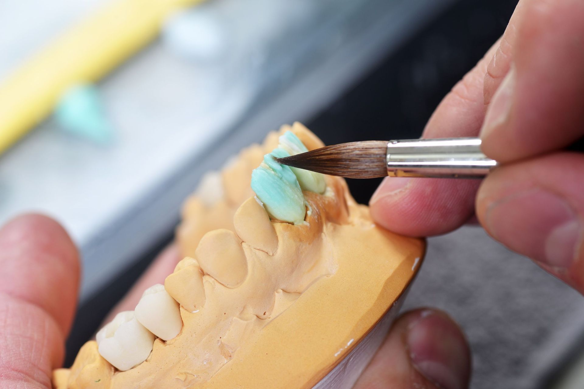 Una persona sostiene un cepillo sobre un modelo de dientes.