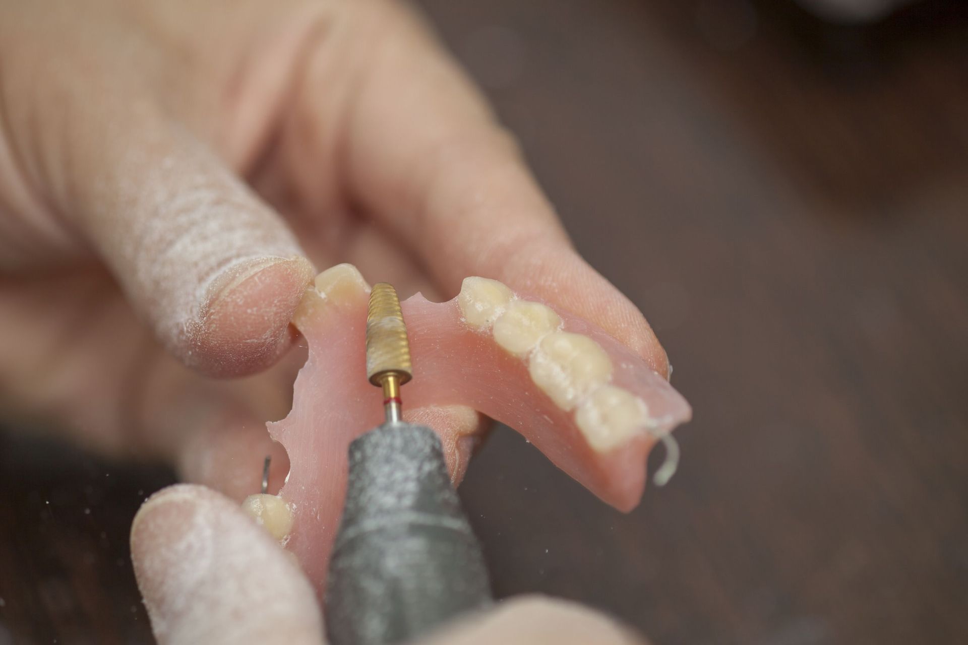 Una persona está puliendo una dentadura postiza con una máquina.