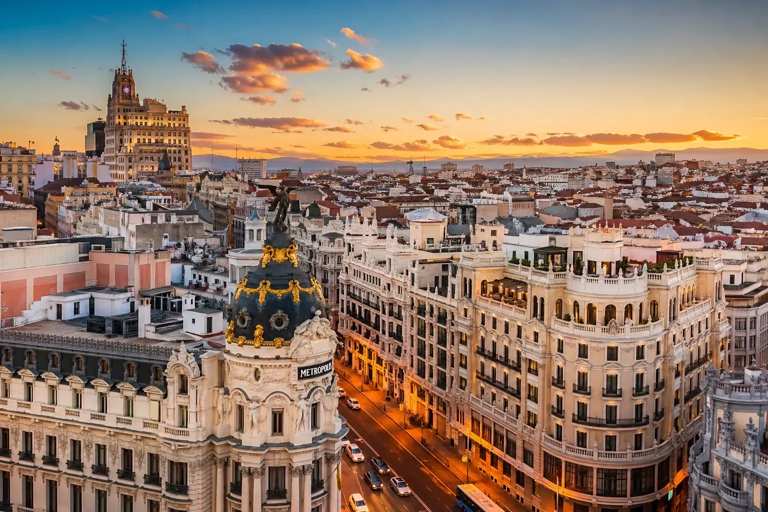 Puesta de sol sobre el paisaje urbano de Madrid con edificios históricos y calles iluminadas.