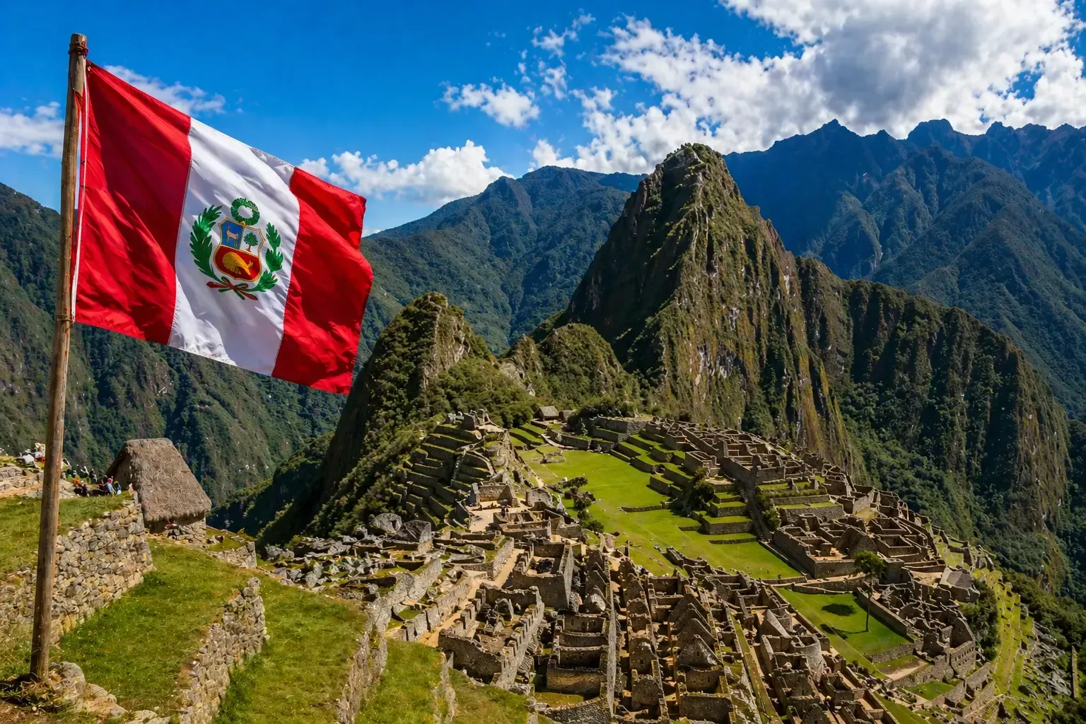 Bandera peruana ondeando sobre las ruinas de Machu Picchu y las montañas bajo un cielo azul.